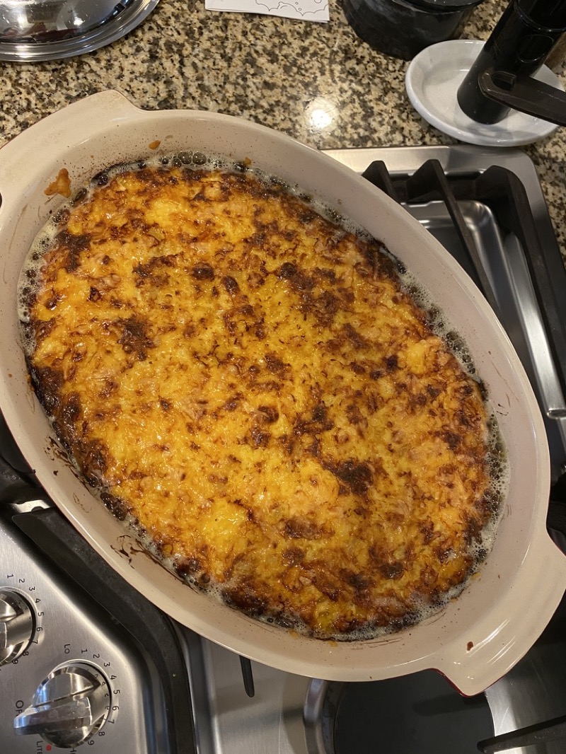 Top-down view of golden baked macaroni and cheese in a casserole dish on a stovetop
