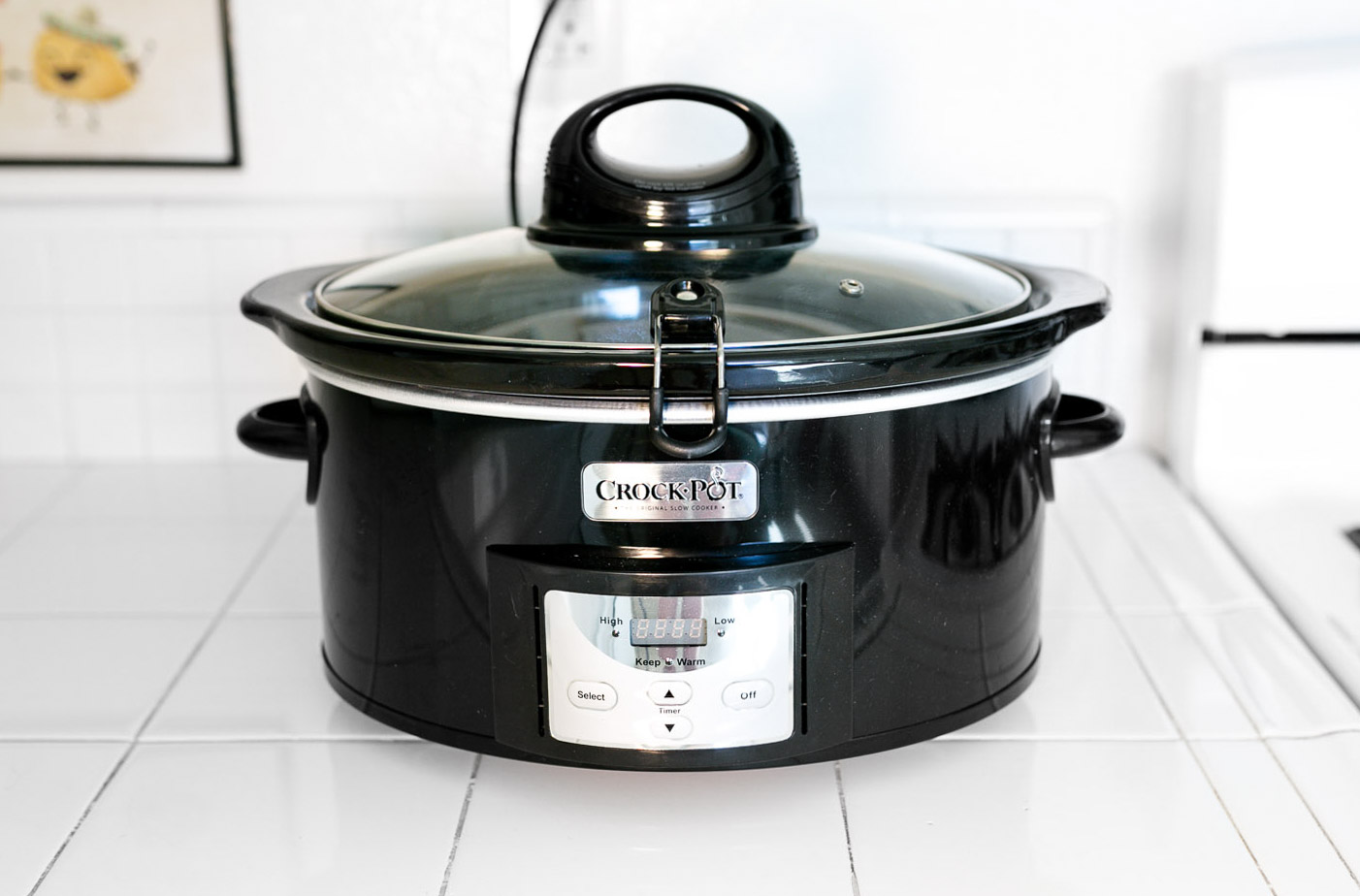 Crock-Pot brand black 6-quart slow cooker on white tile counter with the digital control panel showing High and Low settings, used for the slow-and-steady cannabutter infusion that powers this cookie recipe