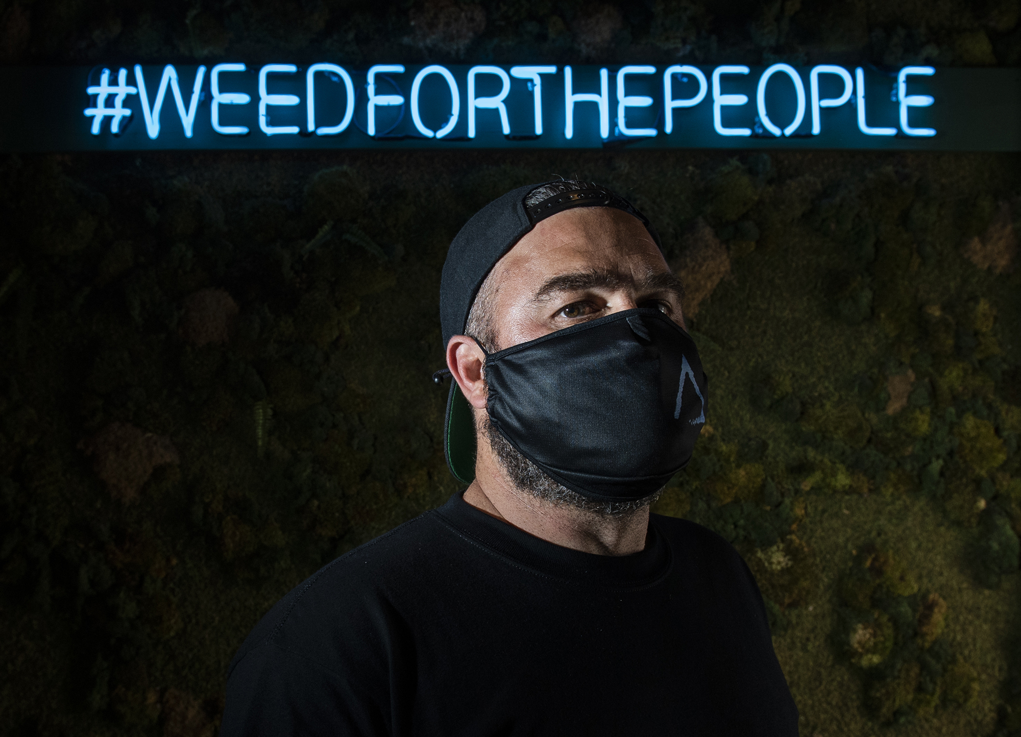 Catalyst Cannabis founder Elliot Lewis inside a Long Beach Catalyst store under the brand's Weed For The People neon