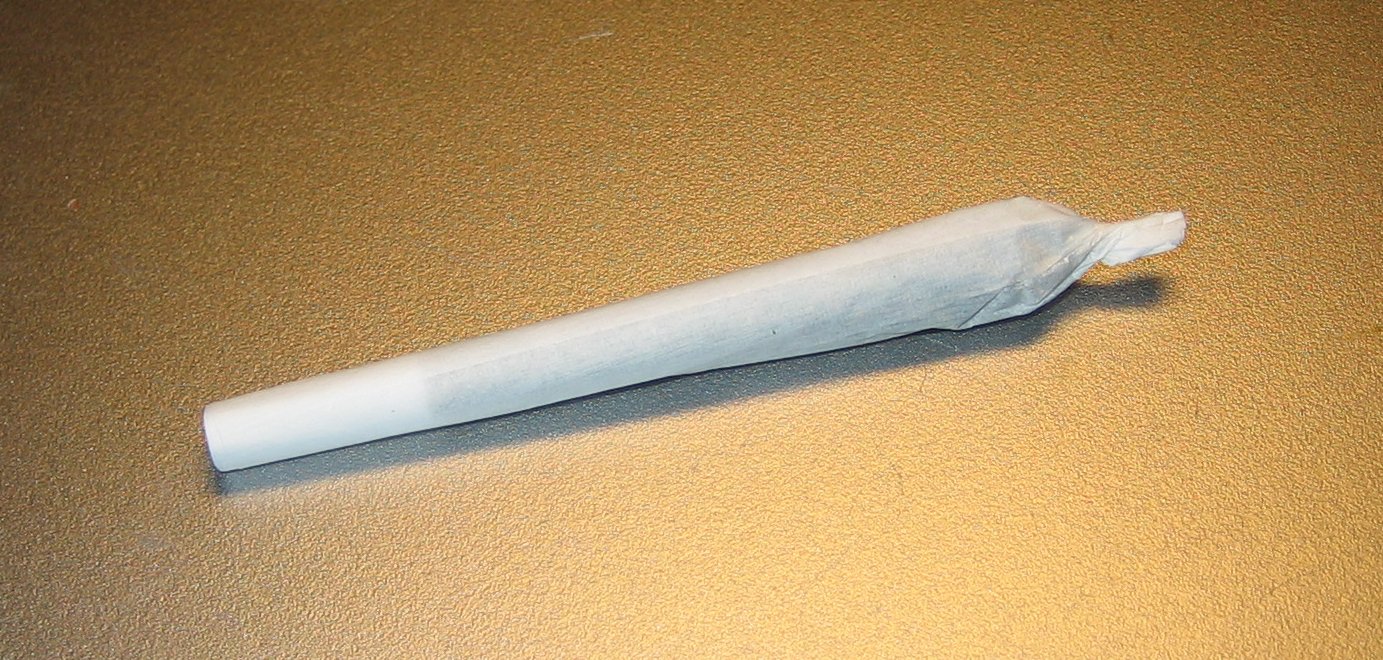 A finished cannabis joint resting on a surface, showing the twisted tip and crutch end