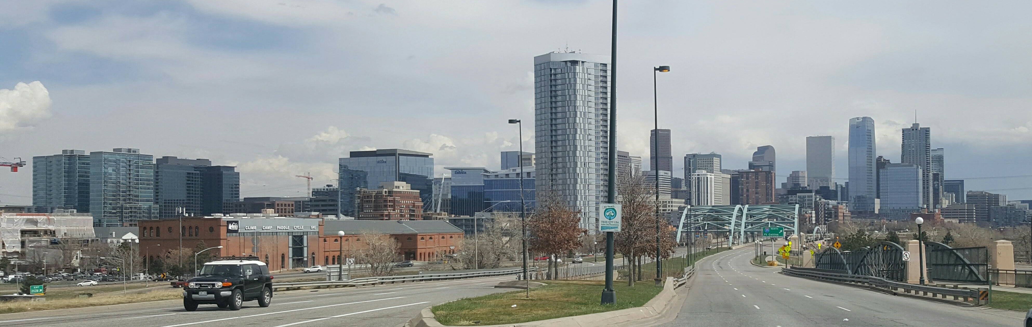 Denver skyline from Speer Boulevard near I-25, showing downtown high-rises against the Front Range