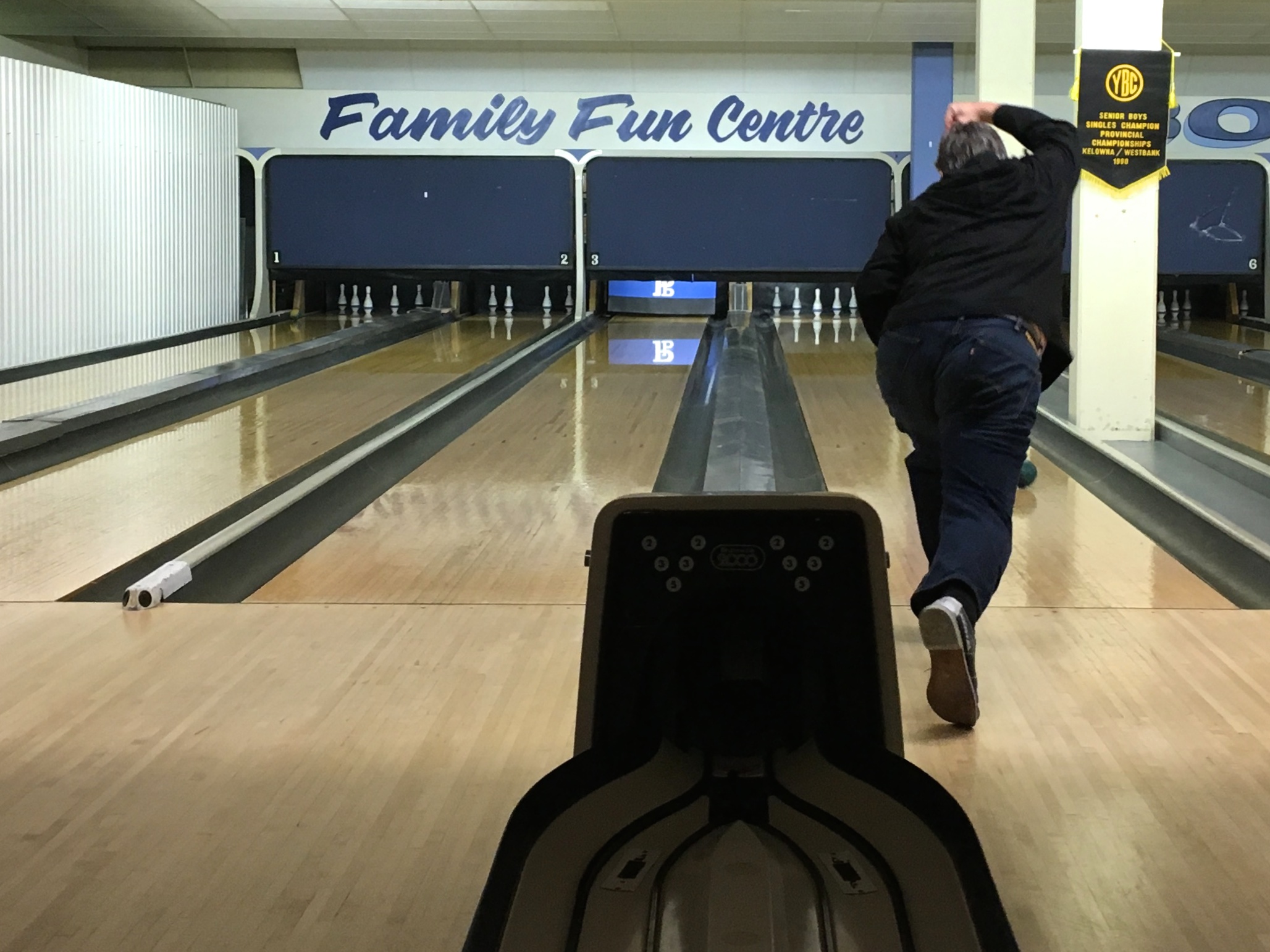 Vintage bowling alley lanes with a player rolling toward the pins evoking the league night setting central to The Big Lebowski