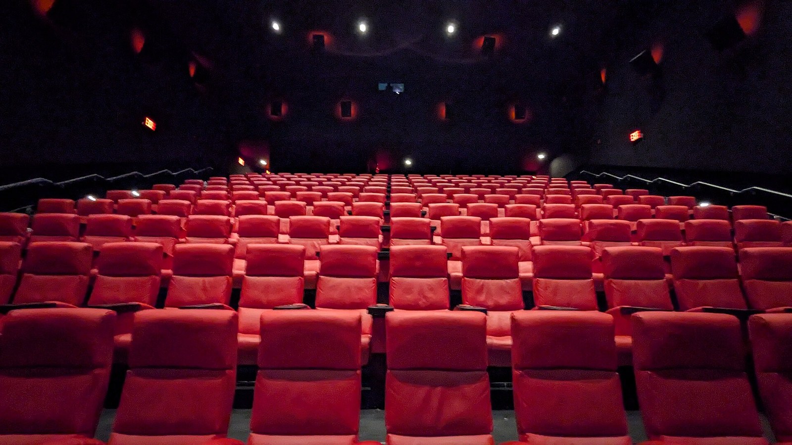 Empty movie theater seats lit in red, illustrating the home theater vibe of a stoner movie night
