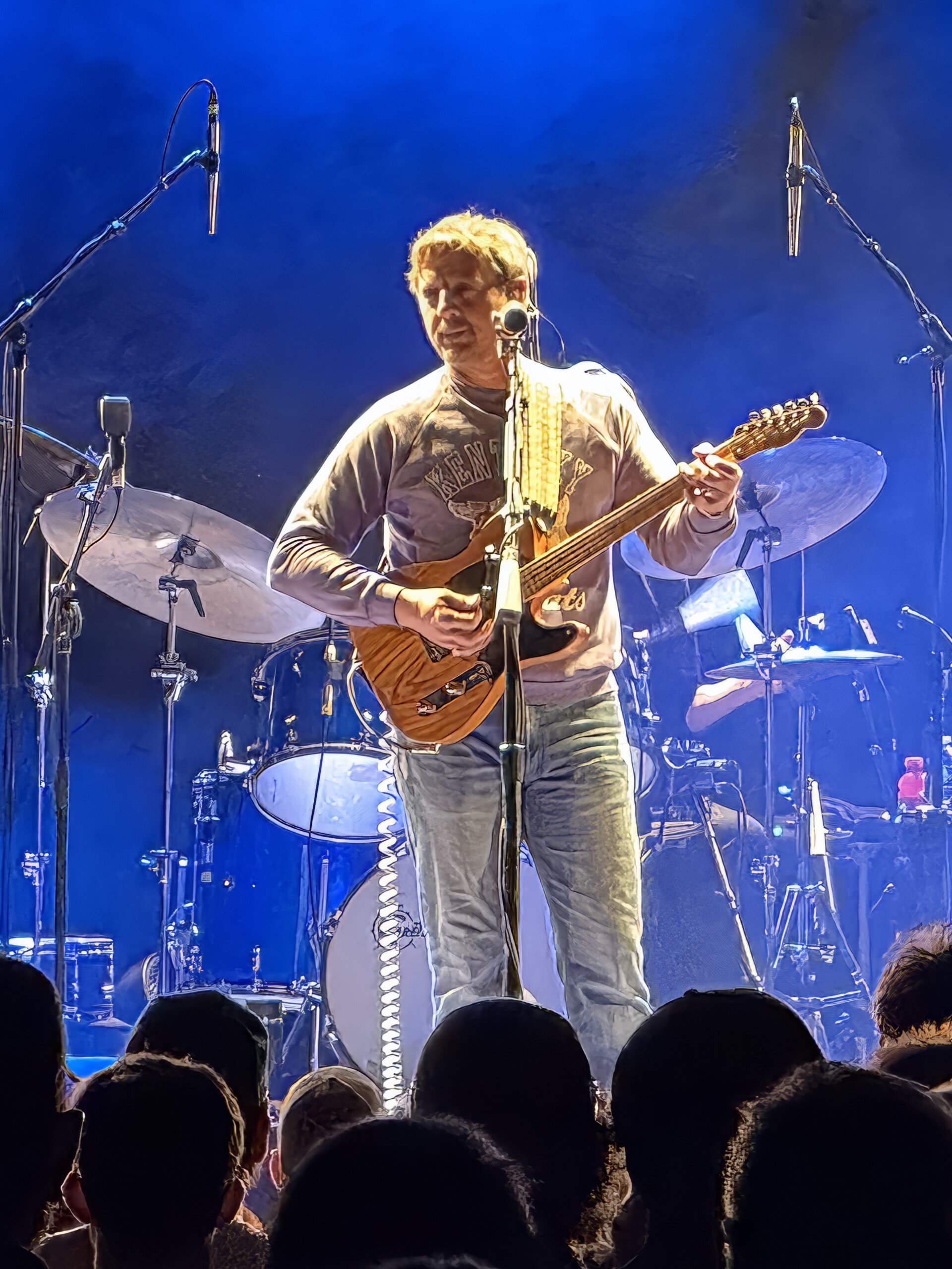 Sturgill Simpson performing as his Johnny Blue Skies stage persona with a bass guitar under blue stage lights, the Kentucky songwriter who put DMT and marijuana into the same verse on Turtles All the Way Down in 2014