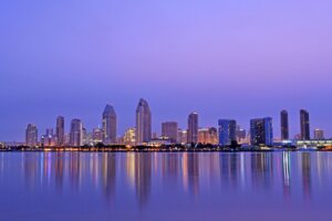 San Diego downtown skyline reflecting in San Diego Bay at dawn, with Coronado in the foreground