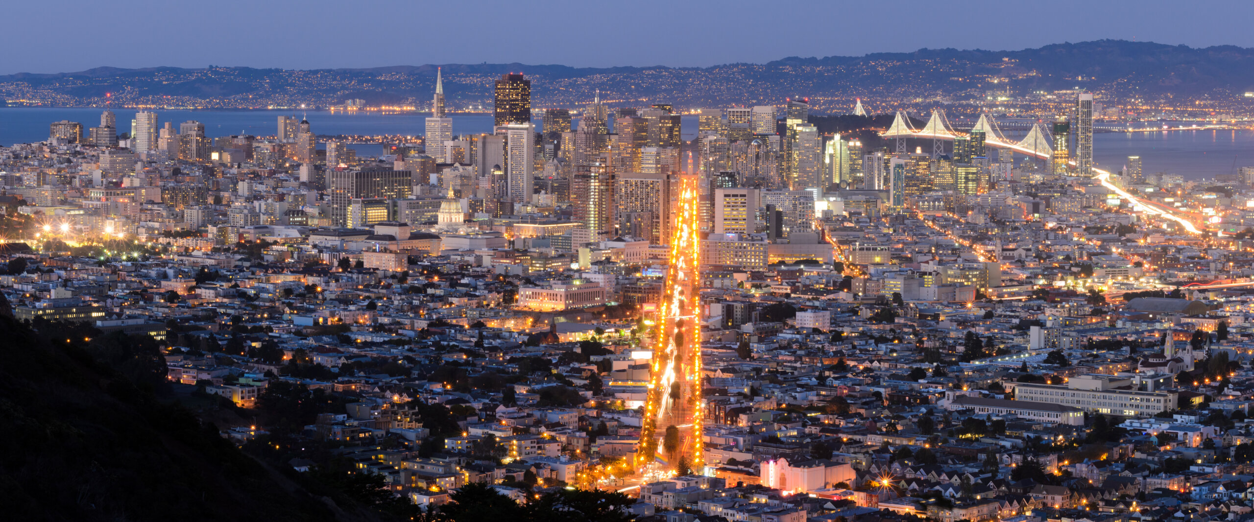 San Francisco downtown skyline panorama from Twin Peaks at night with the Bay Bridge and Market Street lights