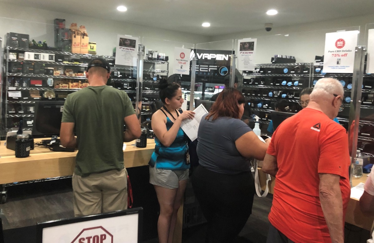 Cannabis dispensary interior with display cases of flower jars and prerolls under recessed lighting
