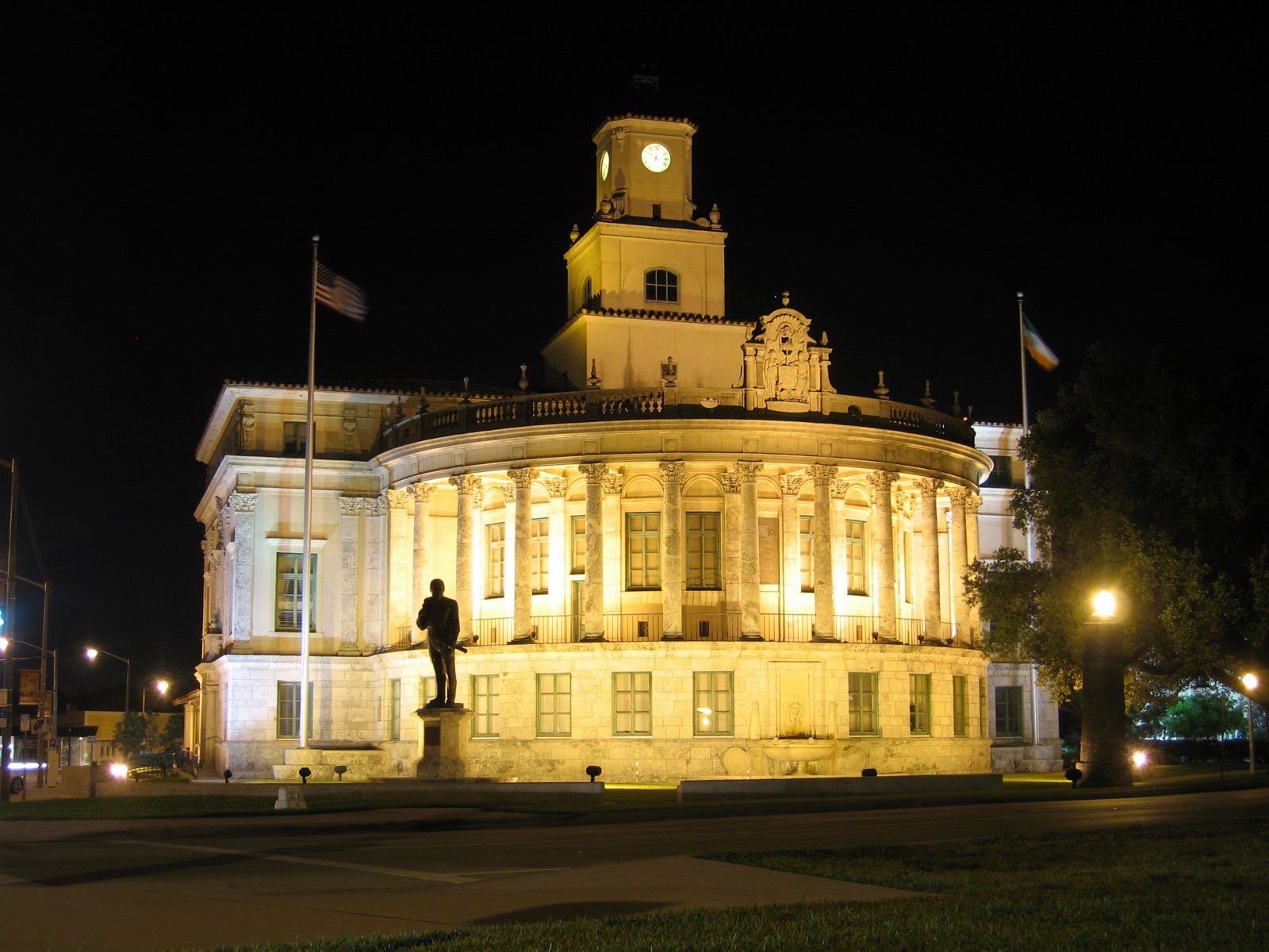 Coral Gables City Hall lit up at night with the clock tower and Florida flags out front