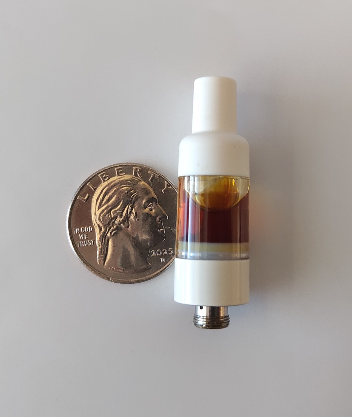 Single 510-thread cannabis live resin cartridge with amber oil next to a US quarter for scale, similar to the Twenty-Two K cart picked up at Ascend Boston