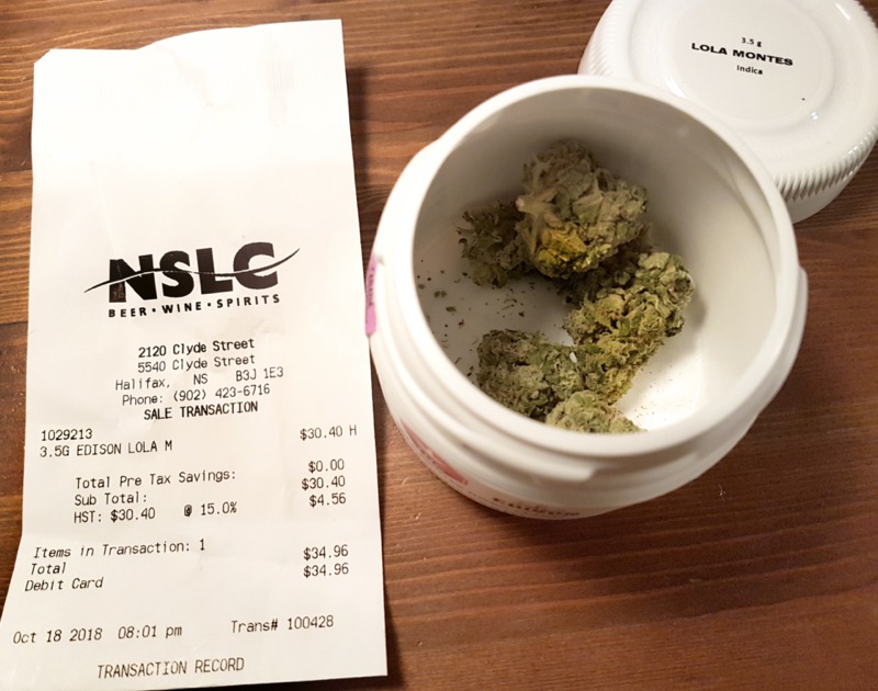 An open 3.5 gram canister of cannabis flower beside a dispensary receipt