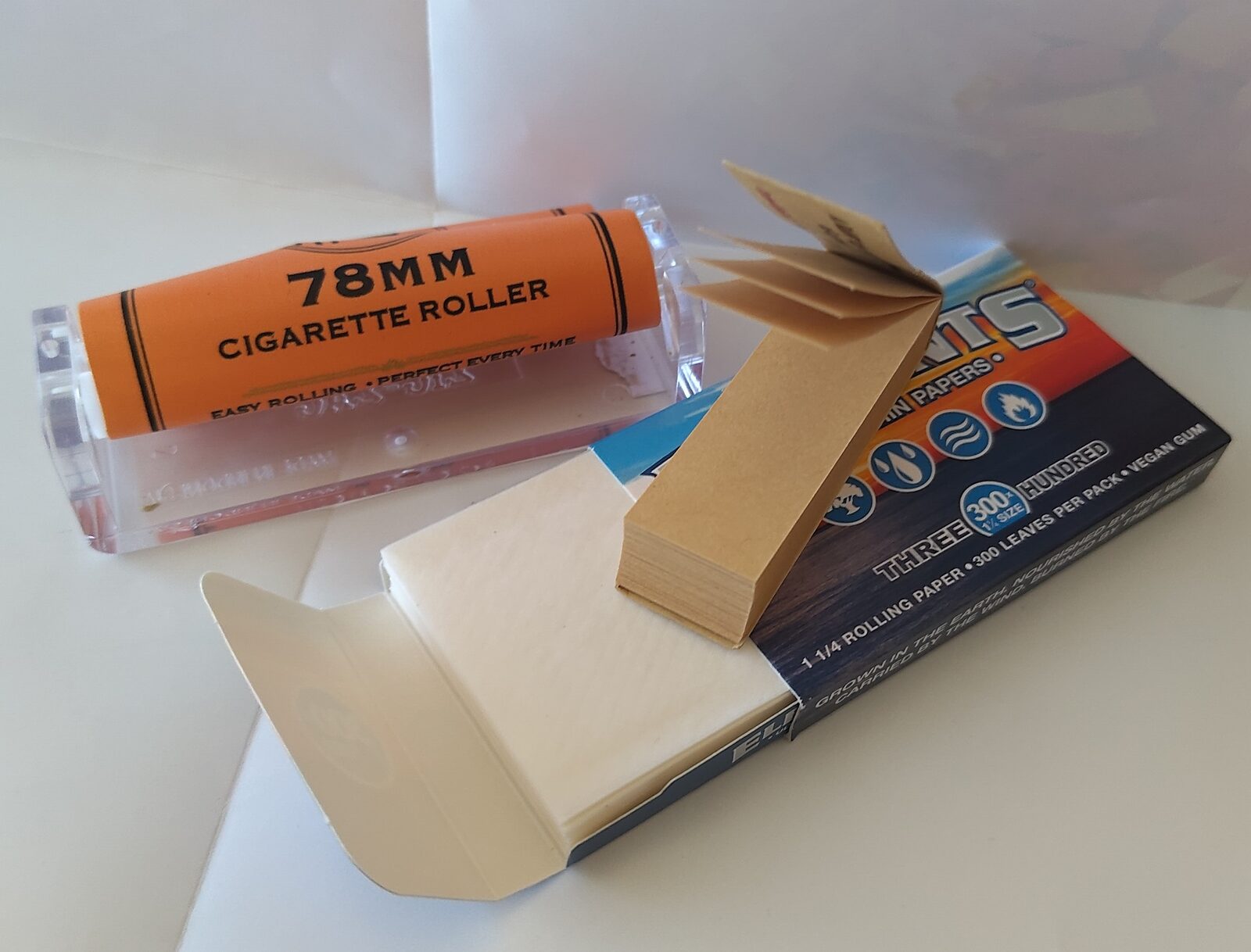Thin cigarette-style rolling papers, a filter tip and ground cannabis laid out together, the lightweight gummed paper that parchment cannot match