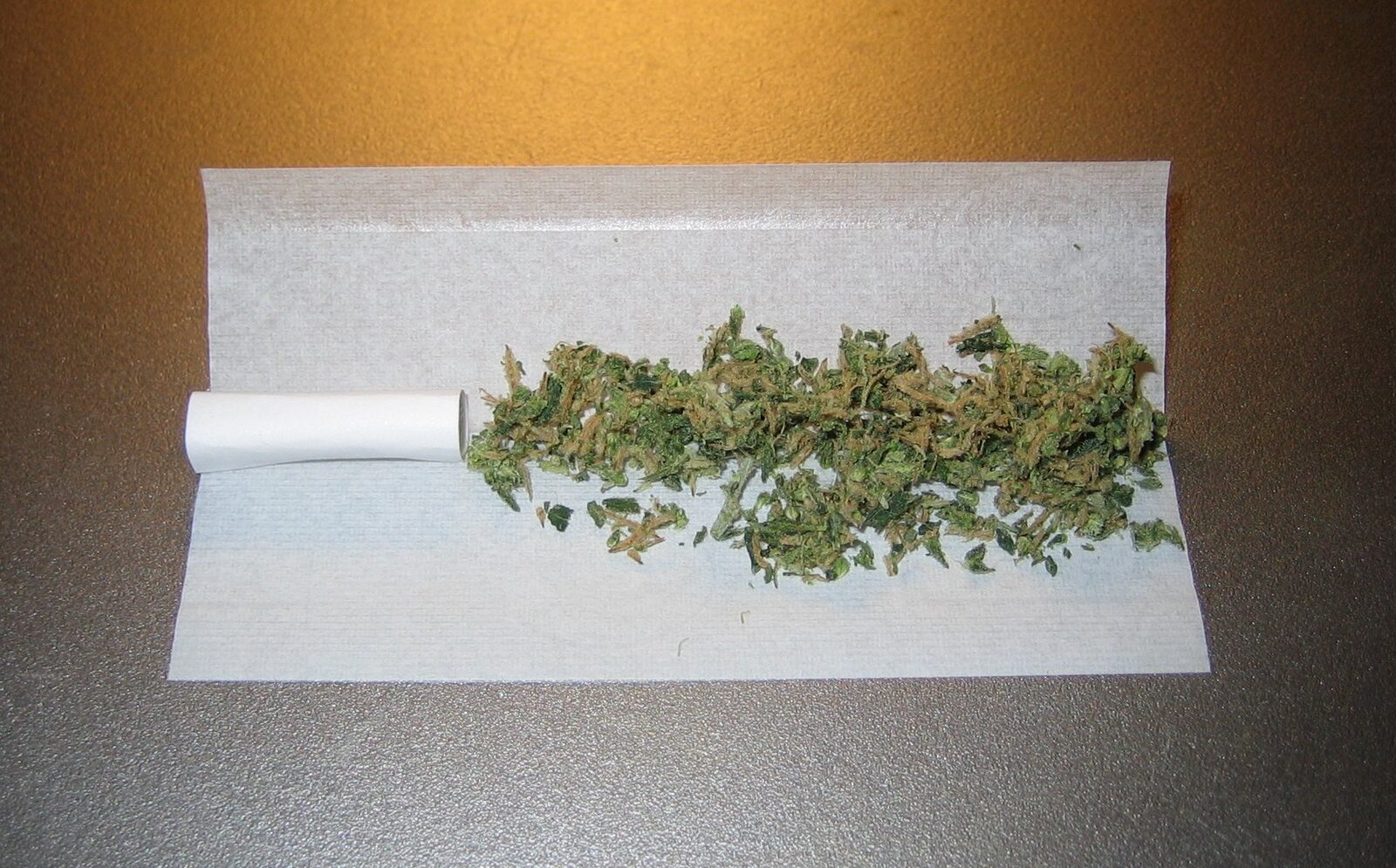 An unrolled cannabis joint showing the thin rolling paper and ground flower, the slow even burn parchment paper cannot reproduce